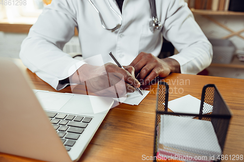 Image of African-american doctor consulting for patient, working in cabinet, close up