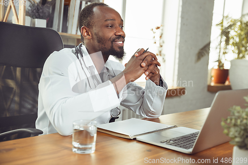 Image of African-american doctor consulting for patient, working in cabinet, close up