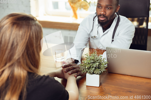 Image of African-american doctor consulting for patient, working in cabinet, close up