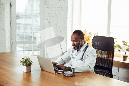 Image of African-american doctor consulting for patient, working in cabinet, close up