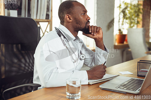 Image of African-american doctor consulting for patient, working in cabinet, close up