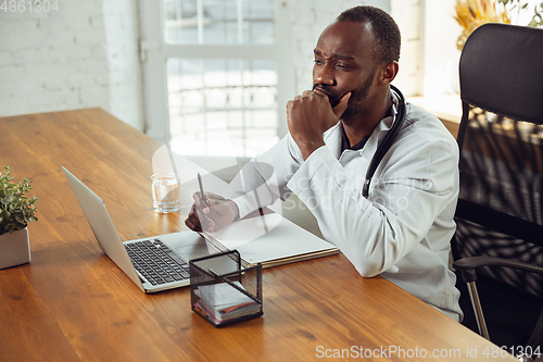 Image of African-american doctor consulting for patient, working in cabinet, close up