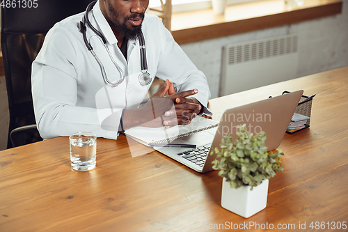 Image of African-american doctor consulting for patient, working in cabinet, close up
