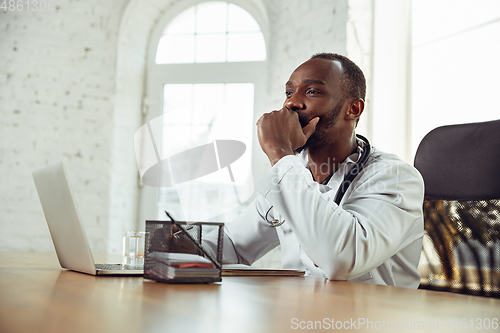 Image of African-american doctor consulting for patient, working in cabinet, close up