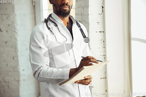Image of African-american doctor consulting, working in cabinet, close up