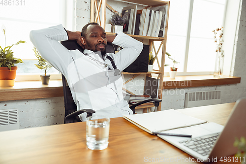 Image of African-american doctor consulting for patient, working in cabinet, close up