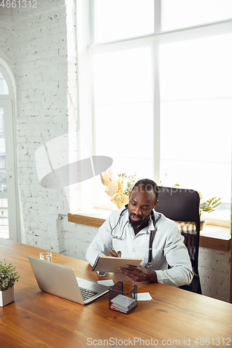 Image of African-american doctor consulting for patient, working in cabinet, close up