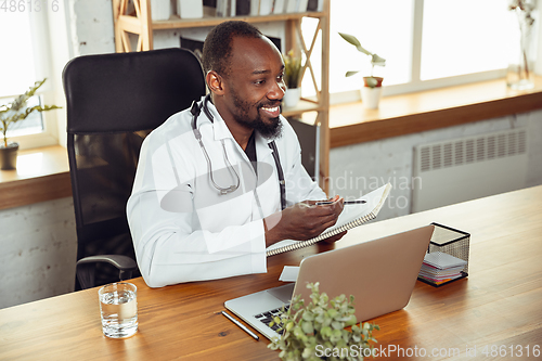 Image of African-american doctor consulting for patient, working in cabinet, close up