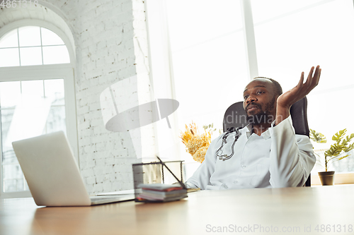 Image of African-american doctor consulting for patient, working in cabinet, close up