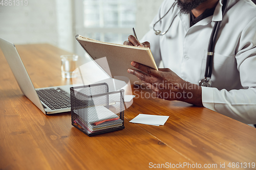 Image of African-american doctor consulting for patient, working in cabinet, close up