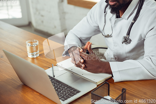 Image of African-american doctor consulting for patient, working in cabinet, close up