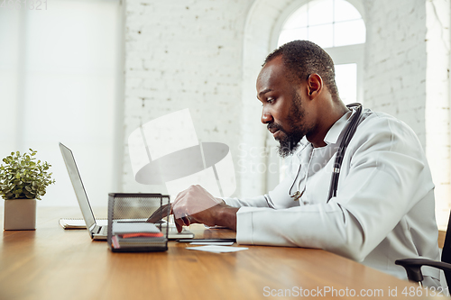 Image of African-american doctor consulting for patient, working in cabinet, close up