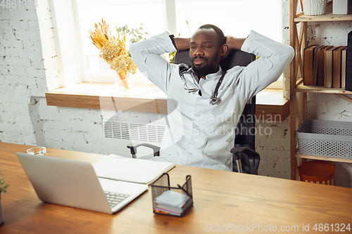 Image of African-american doctor consulting for patient, working in cabinet, close up