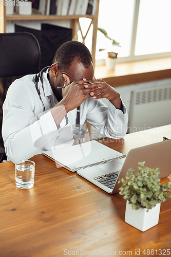 Image of African-american doctor consulting for patient, working in cabinet, close up