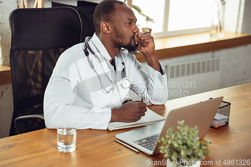 Image of African-american doctor consulting for patient, working in cabinet, close up