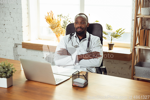 Image of African-american doctor consulting for patient, working in cabinet, close up