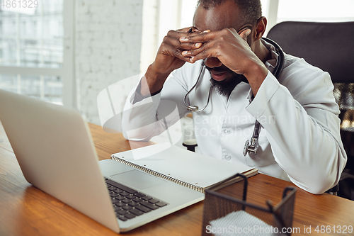 Image of African-american doctor consulting for patient, working in cabinet, close up