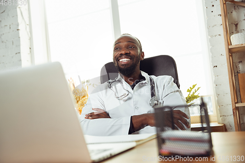 Image of African-american doctor consulting for patient, working in cabinet, close up