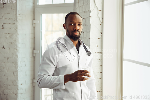 Image of African-american doctor consulting, working in cabinet, close up