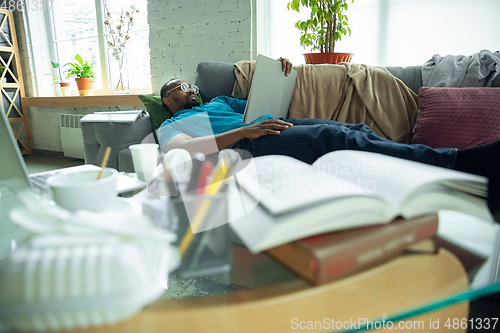 Image of African-american man staying at home during quarantine because of coronavirus spreading