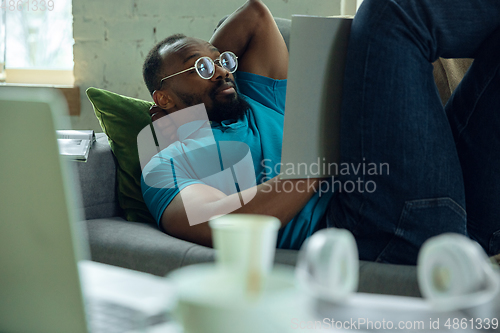 Image of African-american man staying at home during quarantine because of coronavirus spreading