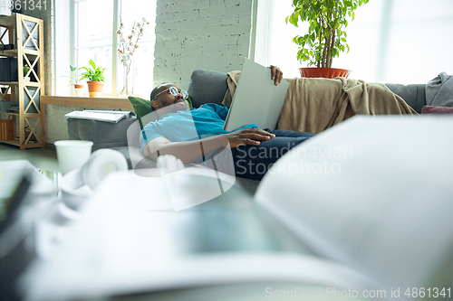 Image of African-american man staying at home during quarantine because of coronavirus spreading