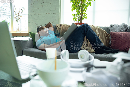 Image of African-american man staying at home during quarantine because of coronavirus spreading