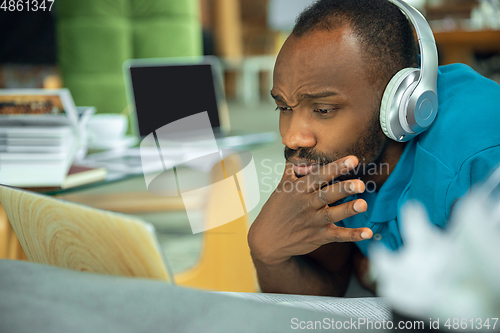 Image of African-american man staying at home during quarantine because of coronavirus spreading