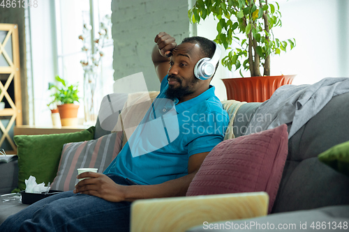 Image of African-american man staying at home during quarantine because of coronavirus spreading