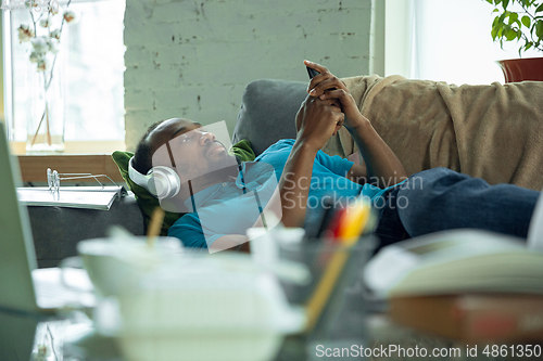 Image of African-american man staying at home during quarantine because of coronavirus spreading