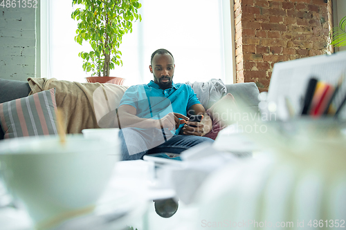 Image of African-american man staying at home during quarantine because of coronavirus spreading