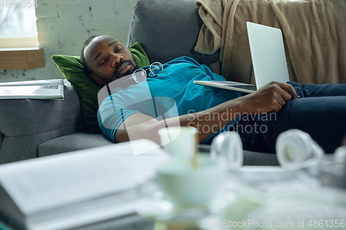 Image of African-american man staying at home during quarantine because of coronavirus spreading