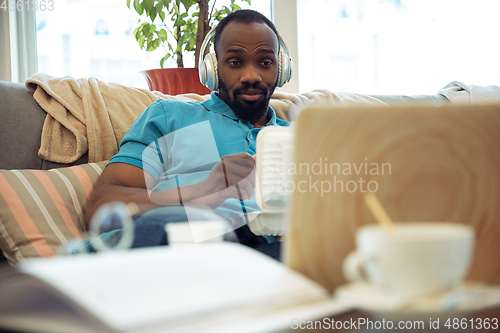 Image of African-american man staying at home during quarantine because of coronavirus spreading