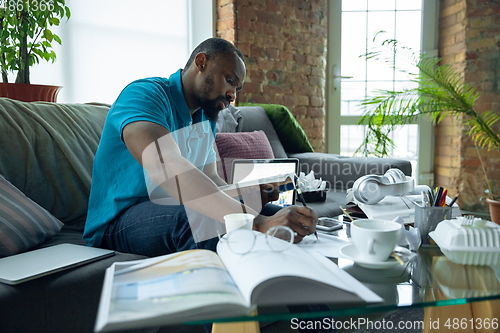 Image of African-american man staying at home during quarantine because of coronavirus spreading