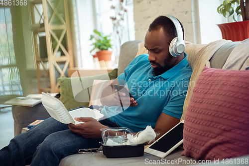 Image of African-american man staying at home during quarantine because of coronavirus spreading