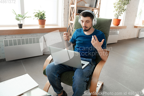 Image of Young focused man studying at home during online courses or free information by hisself