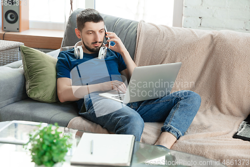 Image of Young focused man studying at home during online courses or free information by hisself