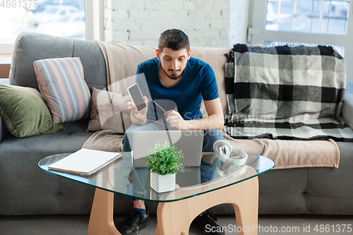 Image of Young focused man studying at home during online courses or free information by hisself