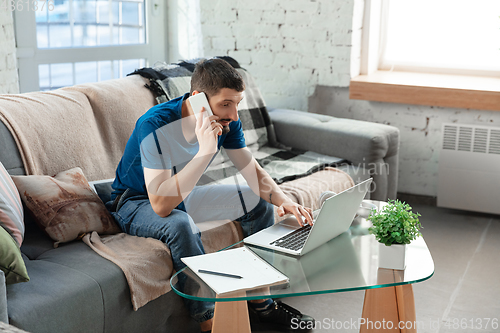 Image of Young focused man studying at home during online courses or free information by hisself