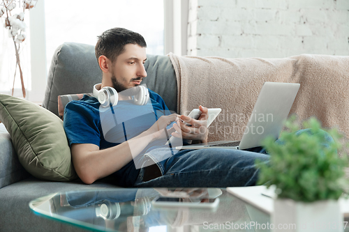 Image of Young focused man studying at home during online courses or free information by hisself