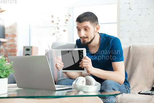 Image of Young focused man studying at home during online courses or free information by hisself