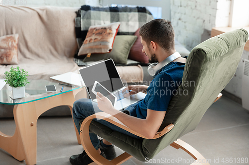 Image of Young focused man studying at home during online courses or free information by hisself