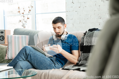 Image of Young focused man studying at home during online courses or free information by hisself