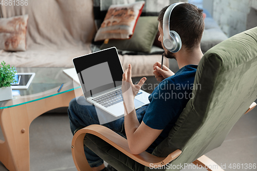 Image of Young focused man studying at home during online courses or free information by hisself