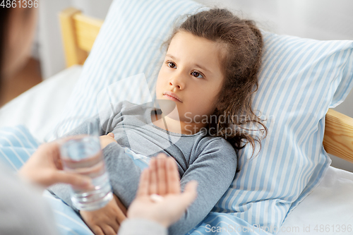 Image of mother giving medicine to sick little daughter