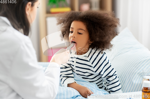 Image of doctor checking sick girl's throat at home