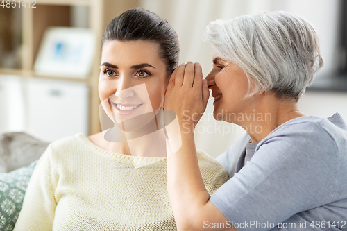 Image of senior mother whispering secret to adult daughter