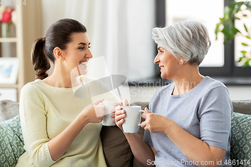 Image of senior mother and adult daughter drinking coffee