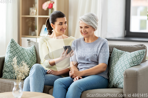 Image of daughter and senior mother with smartphone at home