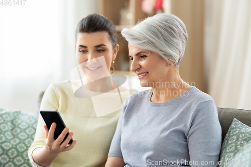 Image of daughter and senior mother with smartphone at home